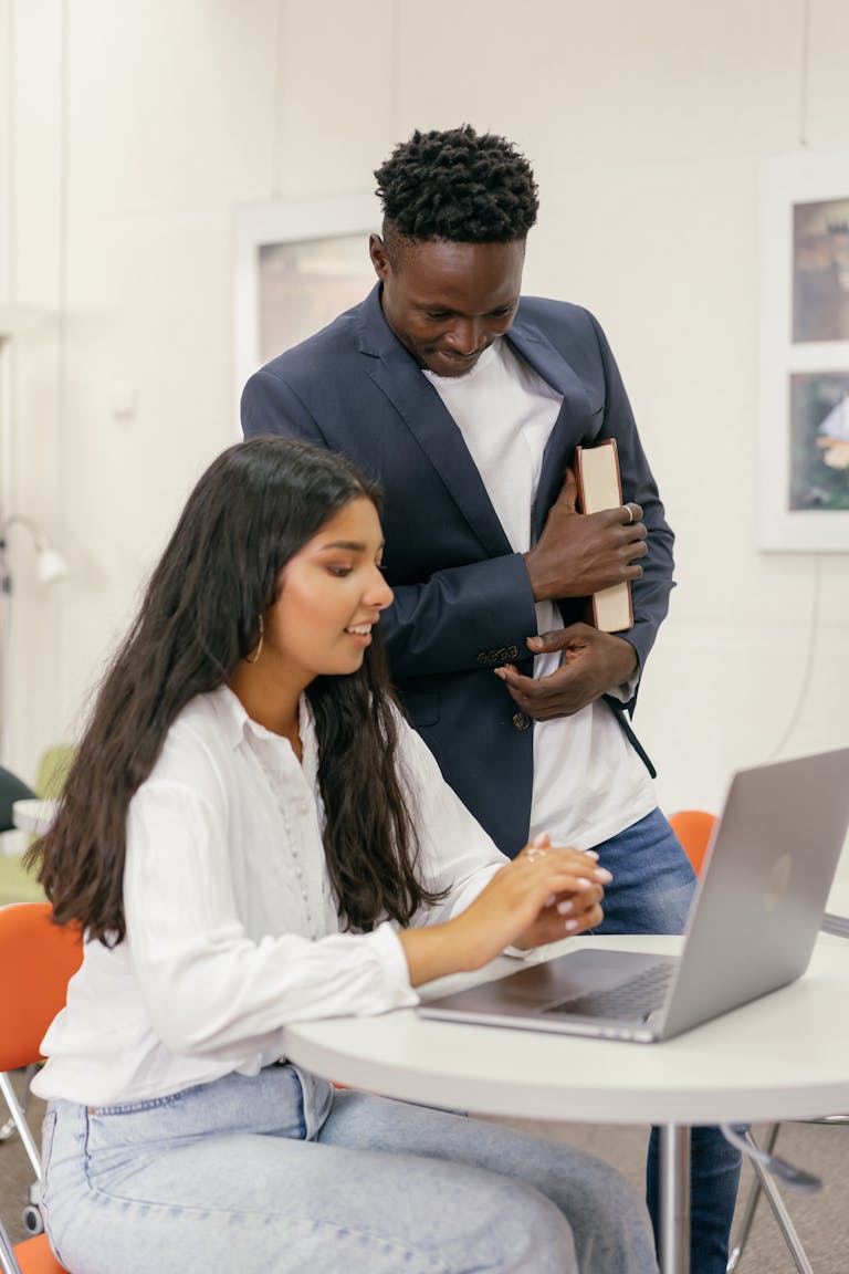 Two students working together on a laptop indoors at college.